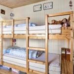 Zwei hölzerne Etagenbetten mit Matratzen und Kissen. An der Wand hängen Bilder und Dekorationen.