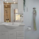 Badezimmer mit Waschbecken, Spiegel und Dusche. Handtuch und Toilettenpapier vorhanden.