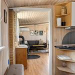 Küche mit Holzwand und Blick in Wohnzimmer mit Sofa und Kamin.