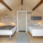 Zwei Betten in einem holzverkleideten Raum mit Dachschräge und Wandbildern.