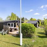 Ein Haus mit Terrasse, Garten und Bäumen unter blauem Himmel.