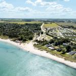 Strand mit Ferienhäusern und Campingplatz in ländlicher Umgebung.