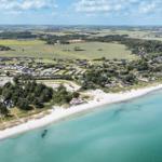 Strandnahe Ferienanlage mit Campingplätzen und Häusern. Weite Landschaft mit Feldern und Bäumen.