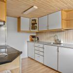 Küche mit Holzdecke, weißen Schränken und Edelstahlspüle.