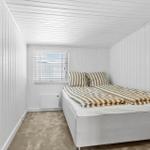 Schlafzimmer mit Bett, Fenster und Wandverkleidung.