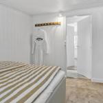 Schlafzimmer mit Bett, Bademantel an Haken und Spiegel an der Wand.