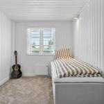 Schlafzimmer mit Bett, Fenster und Akustikgitarre.