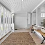 Helle Veranda mit Holzbank, Handtuchrollen und Blick auf Garten