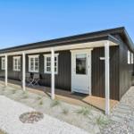 Moderne Holzhütte mit Veranda, Garten und Feuerstelle.