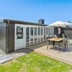 Moderne Villa mit Terrasse, Garten und Sitzgruppe unter Sonnenschutz.