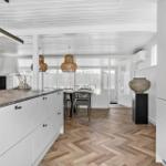 Moderne Küche mit weißem Schrank und Marmorarbeitsplatte. Holzfußboden und Essbereich im Hintergrund.