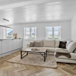 Wohn- und Küchenbereich mit Sofa, Tisch und Holzboden.