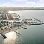 Aerial view of harbor with boats, beach, and surrounding town.