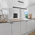 Moderne Küche mit weißen Schränken, Steinplatte und integriertem Ofen.