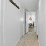 Flur mit weißen Wänden und Teppichboden. Durchgang zu Esszimmer mit Tisch und Lampe.