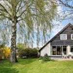 Haus mit großem Garten und Bäumen. Terrasse mit Tisch und Stühlen. Glasfront zur Aussenterrasse.