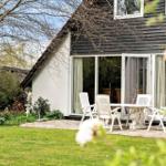 Haus mit Garten, Terrasse und weißem Tisch mit Stühlen.