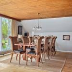 Esszimmer mit Holzdecke, großem Fenster und Esstisch mit acht Stühlen.