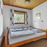 Schlafzimmer mit Holzbett, Fenster und Holzdecke.