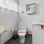 Badezimmer mit Toilette, Waschmaschine und Spiegel an der Wand.