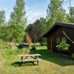 Holzhütte mit Grillplatz und Picknicktisch im Grünen.