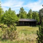 Holzhütte mit Veranda im Wald, umgeben von Gras und Bäumen.