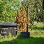 Außenwhirlpool mit Holzbecken und Heizung im Grünbereich.