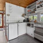 Küche mit weißen Schränken, Edelstahlspüle und Fenster zur Außenseite.