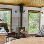 Wohnraum mit Kamin, Sofa und Blick auf Wald.