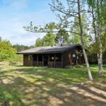 Holzhütte mit Terrasse im Grünen, umgeben von Bäumen und Gras.