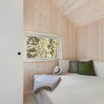 Schlafzimmer mit Holzwand und Fensterblick auf Bäume