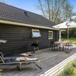 Holzterrasse mit Sonnenliegen, Grill und Tisch mit Sonnenschirm.