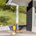 Außenbereich mit Tisch, Stühlen und Frühstück. Im Hintergrund Gras und Spielzeug.