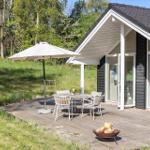 Terrasse mit Tisch, Stühlen, Sonnenschirm und Feuerkorb vor einem Haus mit Glasfront.