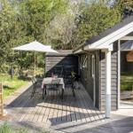 Terrasse mit Tisch, Stühlen und Sonnenschirm. Holzterrasse, umgeben von Grün.