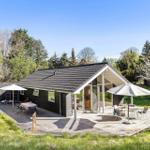 Moderne Hütte mit Holzterrasse, Gartenmöbeln und Blick auf Wälder.