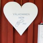 Herz mit Willkommensschild an roter Holzwand