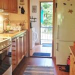 Küche mit Holzschränken, Kühlschrank und Blick auf Balkon.