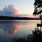 See bei Sonnenuntergang mit Boot und Bäumen