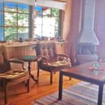 Wohnzimmer mit Holzwand, Kamin, zwei Sesseln und Holztisch.