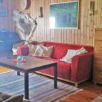 Ein Wohnzimmer mit rotem Sofa, Holzwand und Holzboden. Es gibt einen Tisch und einen Teppich.