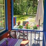 Terrasse mit Tisch, Stühlen und Sonnenschirm. Blick auf grünen Garten und Wald.