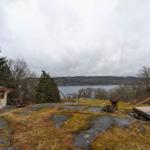 Haus mit Blick auf See, Holzterrasse und Grillplatz auf Steinflur.