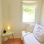 Ein Schlafzimmer mit weißem Bett, Fenster und Nachttisch mit Lampe.