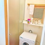 Waschmaschine in einem kleinen Raum mit Schiebetür und Regal.