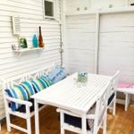 Weißer Holzterrasse mit Tisch, Stühlen und Kissen.