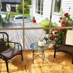 Terrasse mit zwei Stühlen und Tisch, Blick auf Grill und Blumen.