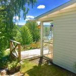Terrasse mit Blick auf Wald und See. Holzgeländer und Glastür.