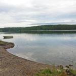 Ein ruhiger See mit kleinem Boot und grüner Umgebung.