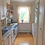 Küche mit Holzboden, Fenster und Küchengeräten